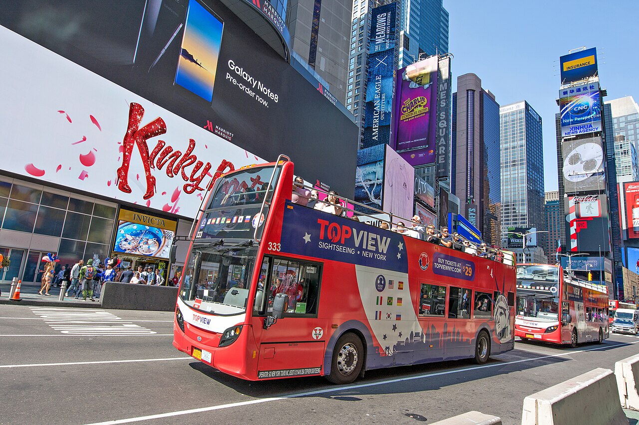 A red double-decker sightseeing bus full of tourists in Times Square, New York