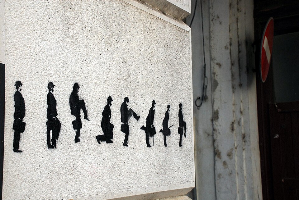 Black silhouettes of men in bowler hats doing silly walks, painted on a wall